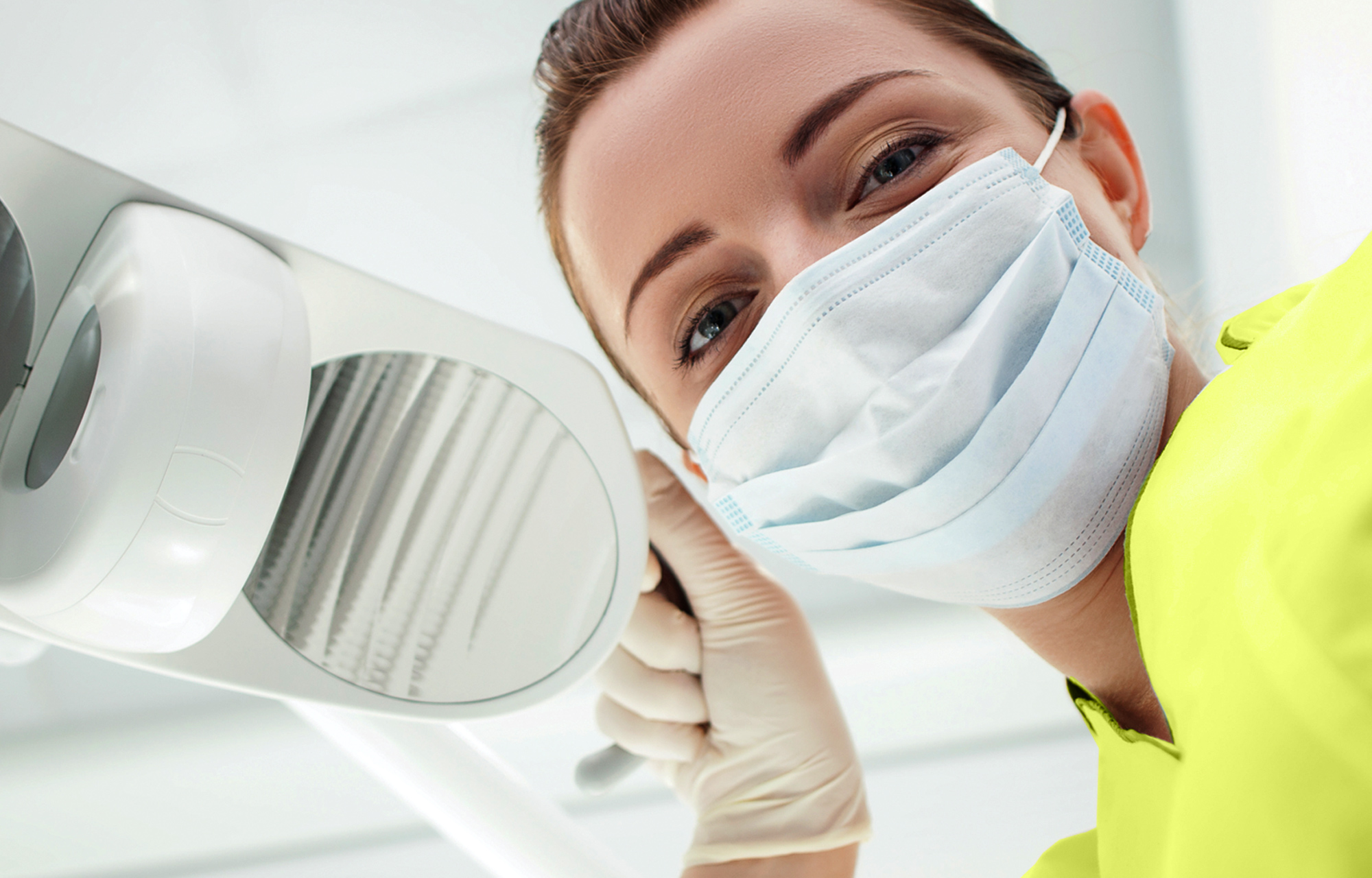 Workers compensation coverage for dental offices - Image of dentist with mask holding light